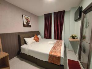 a small bedroom with a bed with white sheets and orange pillows at Hotel Mawar Inn in Jenjarum