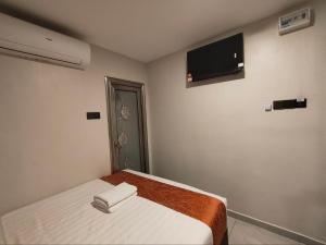 a bedroom with a bed and a flat screen tv at Hotel Mawar Inn in Jenjarum