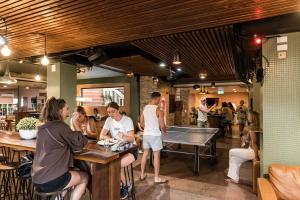 a group of people sitting at a bar with a pool table at Aquarius Backpackers Resort in Byron Bay