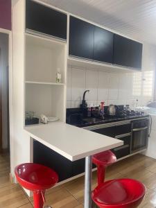 a kitchen with two red stools and a white counter top at Posada - Letiéle in São Gabriel
