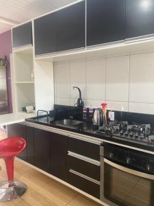 a kitchen with a stove and a sink and a red stool at Posada - Letiéle in São Gabriel +4 photos