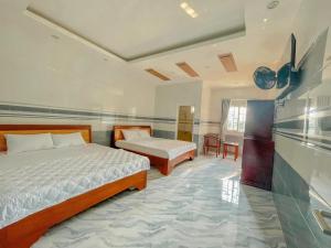 a bedroom with two beds and a table and chairs at Mỹ Lệ Motel in Ho Tram