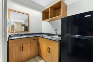 a kitchen with a black refrigerator and a sink at HomeTowne Studios by Red Roof Buffalo - Niagara Airport in Williamsville +21 photos