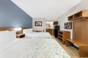a hotel room with two beds and a flat screen tv at HomeTowne Studios by Red Roof Buffalo - Niagara Airport in Williamsville
