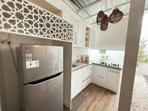 a kitchen with a stainless steel refrigerator and white cabinets at Homestay Aesthetic Jogja in Gondowulung
