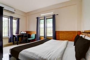 a bedroom with a bed and a desk and windows at Super Hotel O Kollamkudimughal Kakkanad Formerly Diamond Inn in Kakkanad