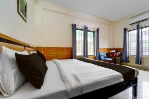 a bedroom with a bed and a desk and windows at Super Hotel O Kollamkudimughal Kakkanad Formerly Diamond Inn in Kakkanad +33 photos