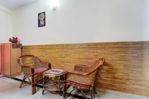two chairs and a table in front of a wall at Super Hotel O Kollamkudimughal Kakkanad Formerly Diamond Inn in Kakkanad