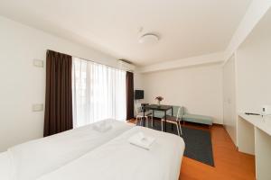 a white bedroom with a bed and a table at Kamata Opus2 Apartment in Tokyo