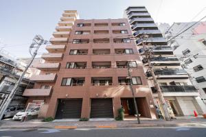 a tall brick building with a parking lot at Kamata Opus2 Apartment in Tokyo