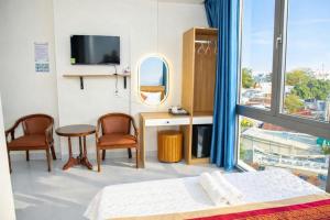 a bedroom with a bed and a desk and a tv at Gia Bảo Hotel Thủ Đức in Ho Chi Minh City