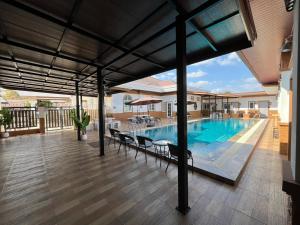 a patio with a pool and chairs and a house at Jin Pool Villa in Ban Khok Chakohan