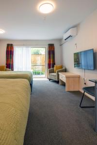 a hotel room with a bed and a couch and a tv at Tussock Peak Lodge in Hanmer Springs