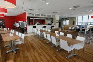 un restaurant avec des tables en bois et des chaises blanches dans l'établissement Travelodge Valencia Aeropuerto, à Manises
