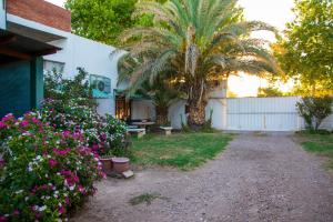 a house with a palm tree and flowers in the yard at Hotel Barcelona in General Alvear