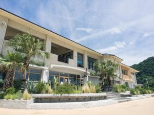 a building with palm trees in front of it at Good Fellows Resort in Kagoshima