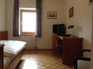 a bedroom with a bed and a desk with a television at Auberge de la Réunion in Coinsins