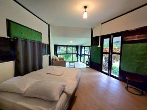 a bedroom with a large bed and large windows at บ้านสุจิปุรี BaanSujipuri in Pak Chong