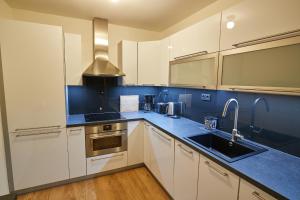 a kitchen with white cabinets and blue counter tops at Kovárna Residence in Pec pod Sněžkou +59 photos