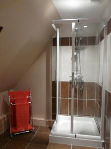 um chuveiro na casa de banho com uma cadeira vermelha em La Bergerie em Suèvres