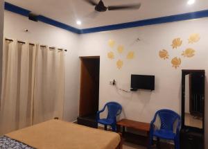 a bedroom with two blue chairs and a bed and a tv at Coorg Relax Home in Madikeri +13 photos