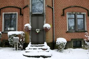 a front door of a brick house covered in snow at Un Air de Château in Spa