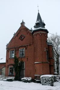 an old brick building with a tower in the snow at Un Air de Château in Spa