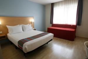 Cette chambre d'hôtel comprend un grand lit et un banc rouge. dans l'établissement Travelodge Torrelaguna, à Madrid