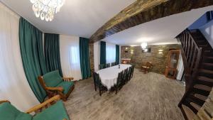 a dining room with a table and green chairs at Cabana Codrii Maramuresului in Giuleşti