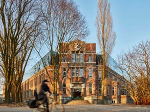 a man riding a bike in front of a building at Generator Amsterdam in Amsterdam