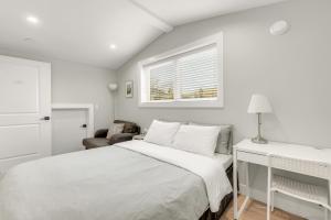 a white bedroom with a bed and a window at New laneway house near Airport, World Cup stadium, Downtown, UBC in Vancouver