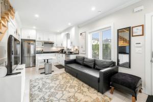 a living room with a black couch and a kitchen at New laneway house near Airport, World Cup stadium, Downtown, UBC in Vancouver