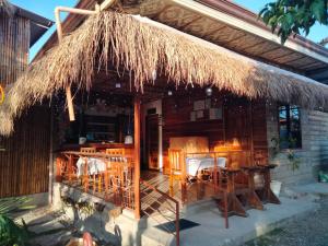 a hut with tables and chairs and a straw roof at The Garden Tropical Cabins in Basdiot