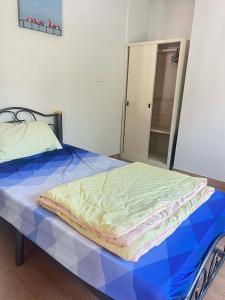 a bed sitting in a bedroom with a blue bedsheet at Baan Phakdee in Ban Phlong Takhe