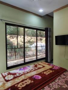 a room with a large window and a rug at Ganesh Cottage in Matheran