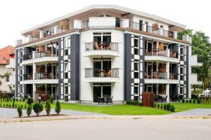 a large white building with balconies and trees at Aparthotel Ostseeperle Glowe - schön gestrandet in Glowe +65 photos