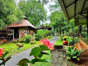 a garden with a house and flowers and a pathway at บ้านสุจิปุรี BaanSujipuri in Pak Chong