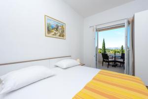 a bedroom with a bed and a balcony with a table at Apartments Aida in Cavtat