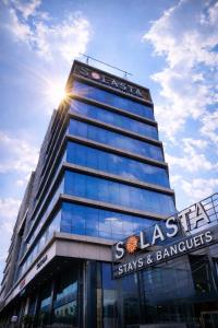 a tall building with the sun shining on it at Solasta Stays and Banquet - Wakad in Pune