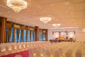 a banquet hall with white chairs and a stage at Solasta Stays and Banquet - Wakad in Pune