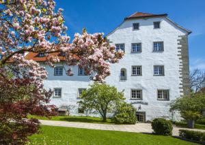 ein weißes Gebäude mit einem Magnolienbaum davor in der Unterkunft Schloss Hotel Wasserburg in Wasserburg