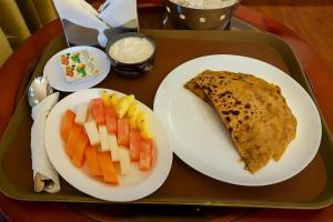 a tray of food with a slice of pizza and fruit at Hotel Vijay Palace Dharamshala Himachal in Dharmsāla