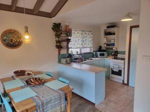 a kitchen with a table and a kitchen with blue cabinets at Ocean Drive Home: 3 bedroom 70s-inspired… - 19110 in Bunbury