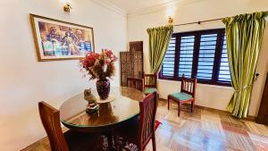 a dining room with a table and a vase of flowers at Scarlets Inn in Cochin +114 photos