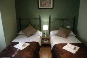 two beds in a room with green walls at Arco de las Descalzas in Úbeda