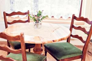 a dining room table with a vase of flowers on it at Agroturystyka Wzgórze Magnolii in Długopole-Zdrój