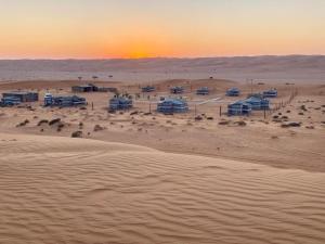 a group of tents in the desert at sunset at Endless Dunes Camp in Badīyah +26 photos