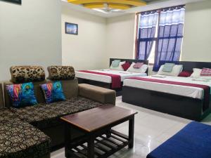 a room with four beds and a couch and a table at Hotel Madurai Comforts in Madurai
