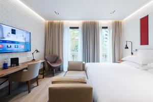 a bedroom with a bed and a desk and a tv at The Corner Hotel in Barcelona