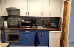a kitchen with blue cabinets and a sink and a microwave at Apartament Lipnicki 2 in Bielsko-Biała
